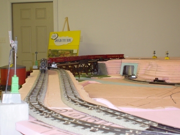 The layout measures 8' x 16'. It is made up of 4 - 4' x '8 tables. Three trains run concurrently on separate loops. All scenery contours are made with foam. The foam is then roughed with a Shur-form tool. This allows application of plaster cloth which accepts paint better and produces a good base for the balance of the scenery.