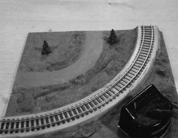This panel is quite different from the production curved panels. The roads crossing the track are absent with a curved road section in its place. There are no mountain foundations. This panel appears to be designed to hold the power supply.
