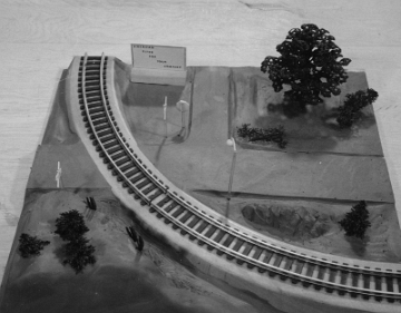 In this panel we see the road junction crossing the tracks. There is a rolling hill on the outside, but no mountain elements on the inside of the curve.